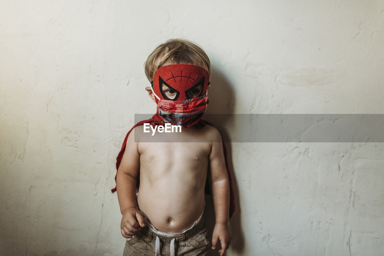 Toddler boy standing in halloween costume and face mask