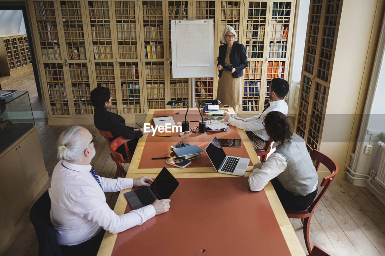 High angle view of senior lawyer giving presentation to coworkers in board room