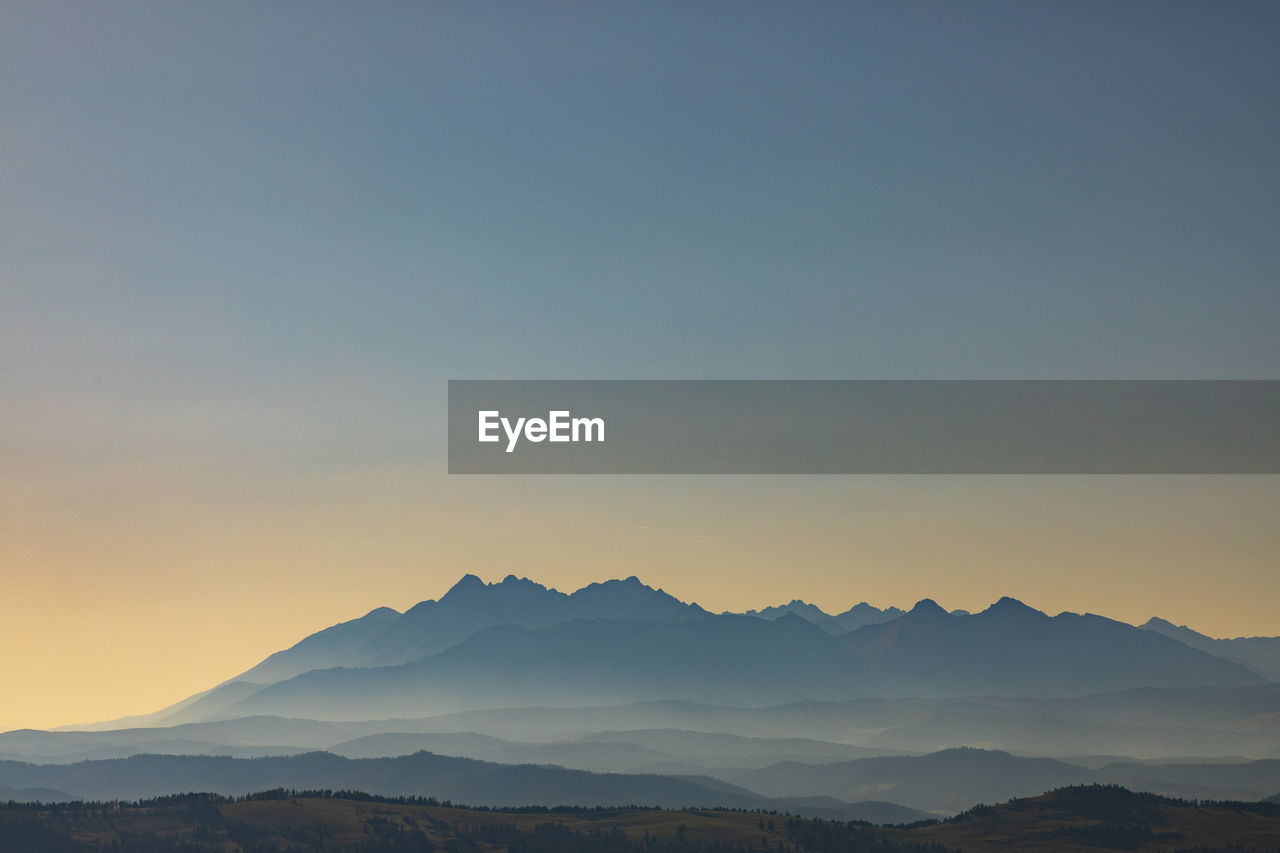 Scenic view of silhouette mountains against clear sky during sunset