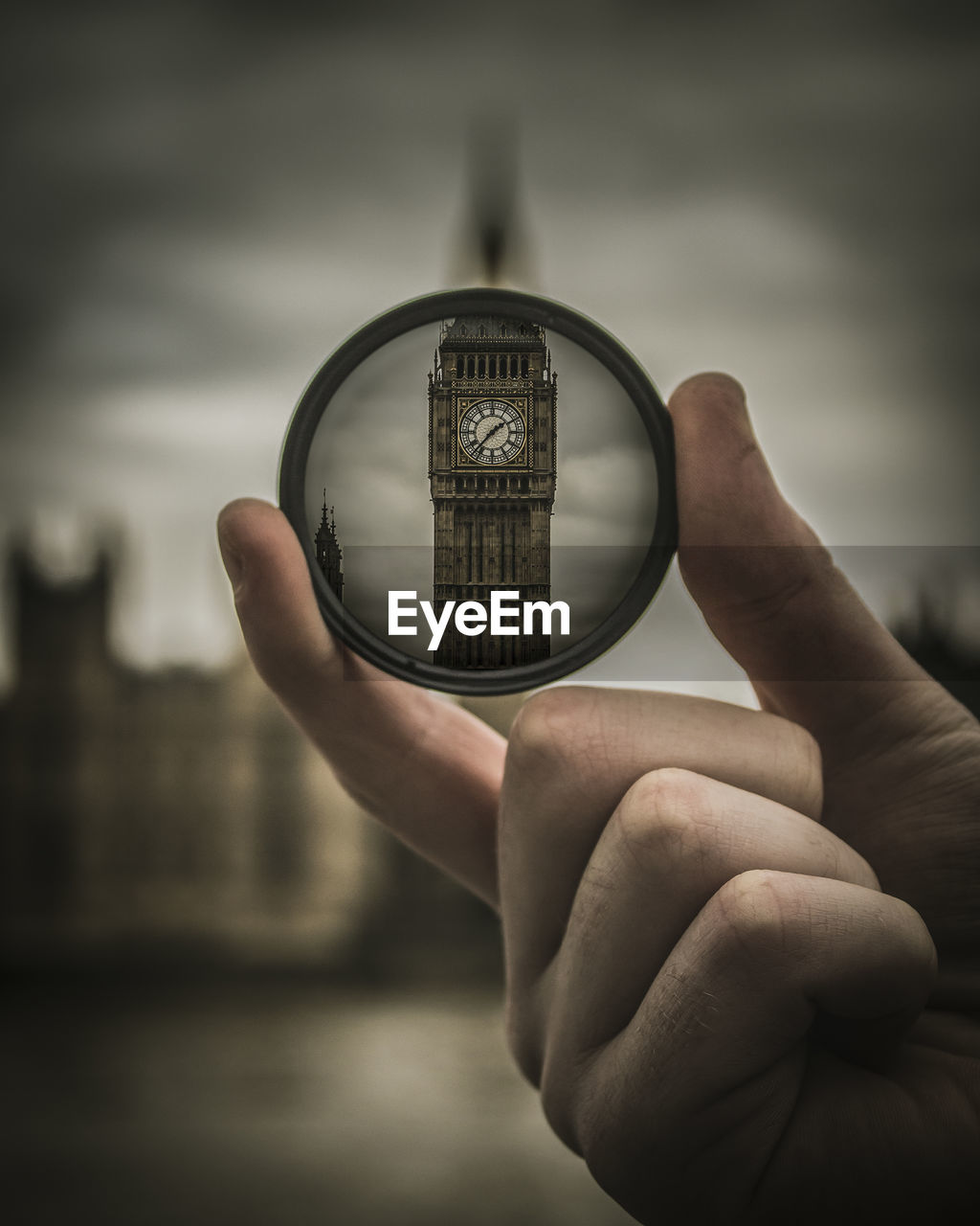 Close-up of hand holding lens against big ben