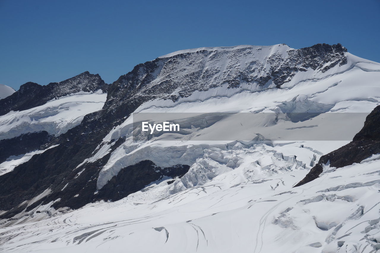 LOW ANGLE VIEW OF SNOWCAPPED MOUNTAIN AGAINST BLUE SKY