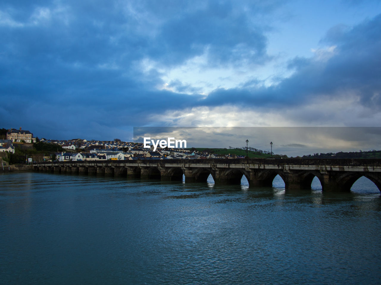 Arch bridge over river against sky in city