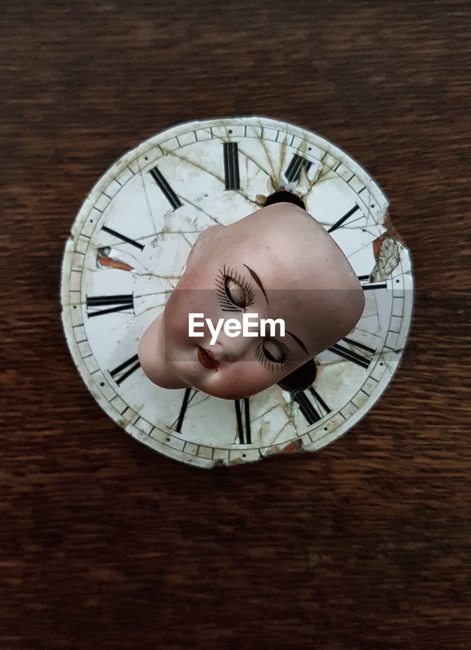 High angle view of doll on weathered clock over table