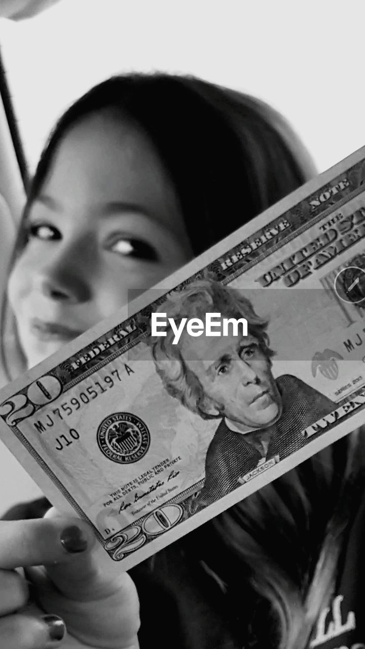 Close-up of smiling woman showing american twenty dollar bill