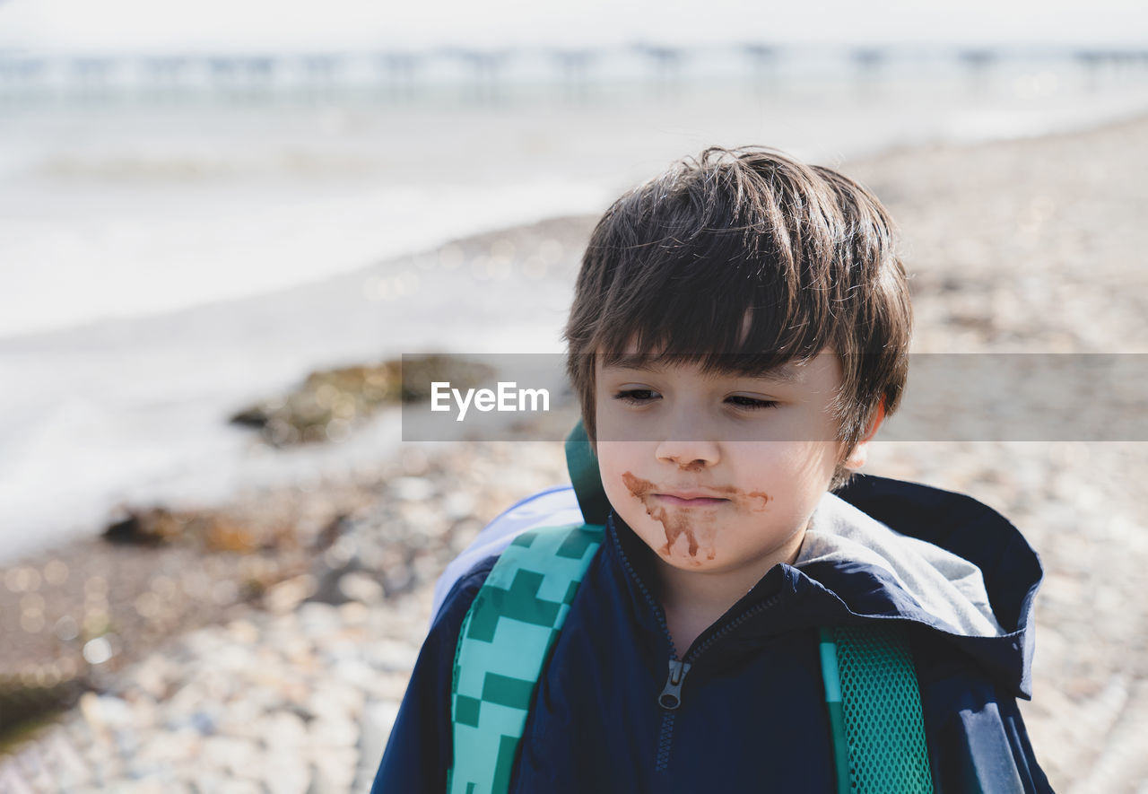 Close-up of boy with messy mouth standing at beach