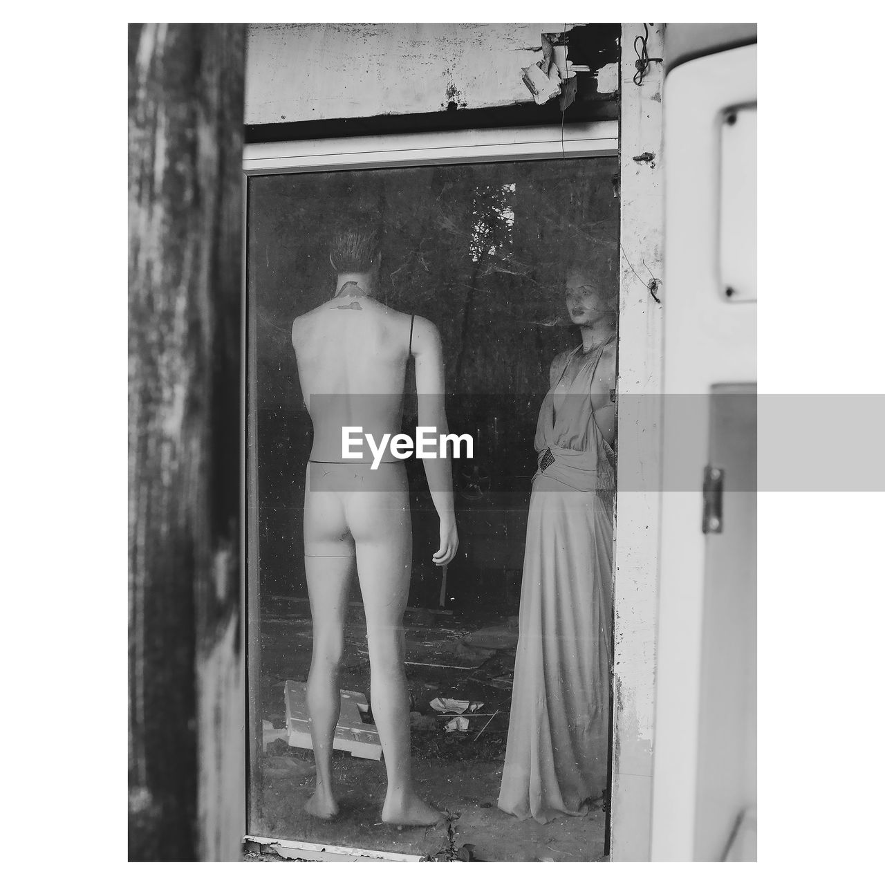 Rear view of shirtless man standing by window