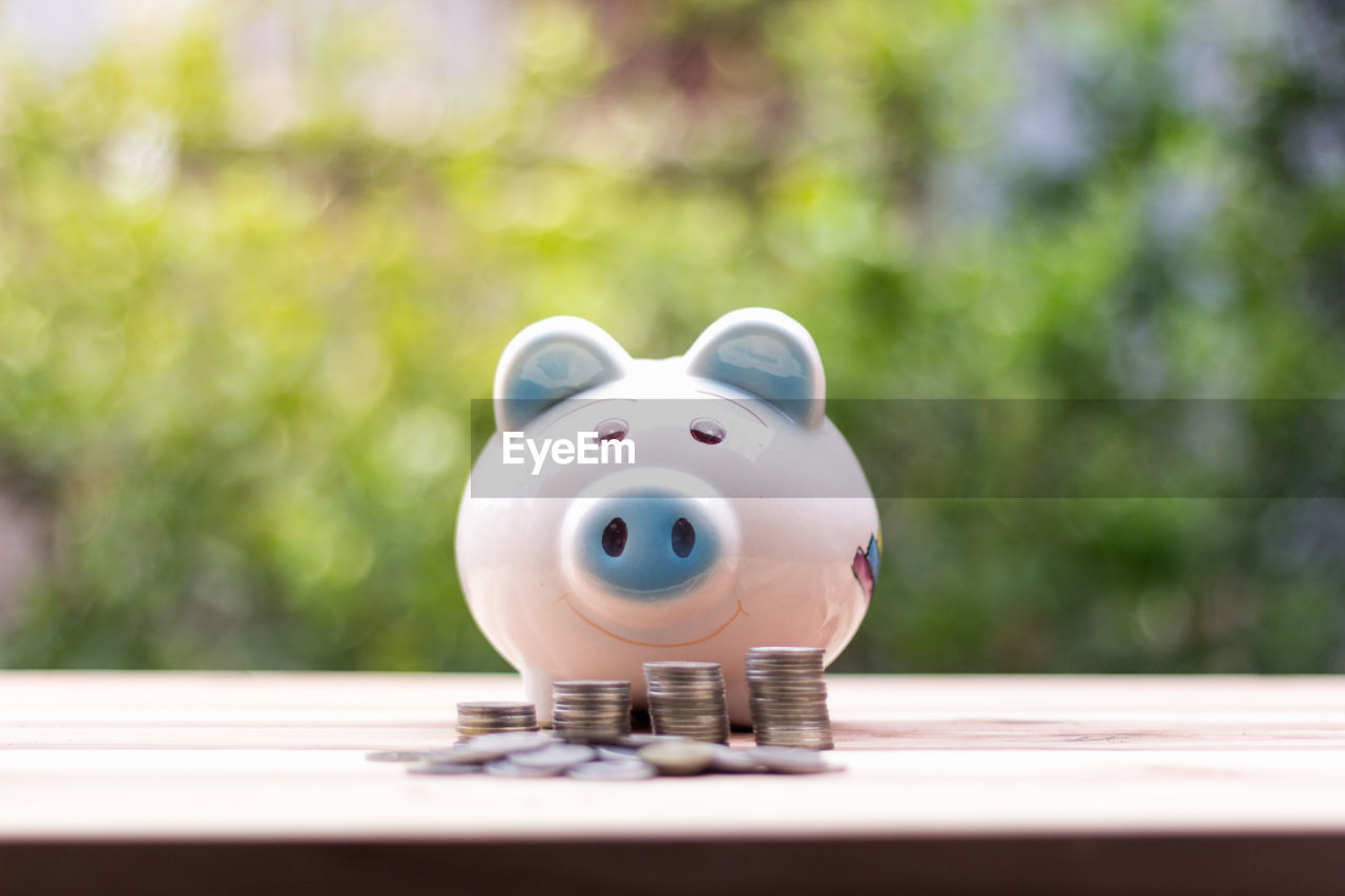 Close-up of piggy bank and coins on table