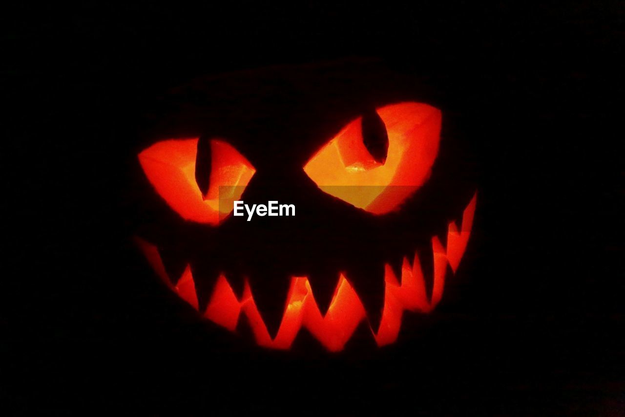 CLOSE-UP OF ILLUMINATED PUMPKIN AT NIGHT