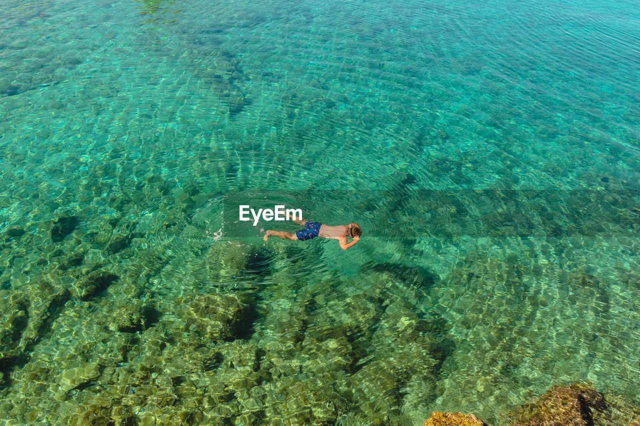 High view of a male snorkeling in crystal clear blue water in croatia.