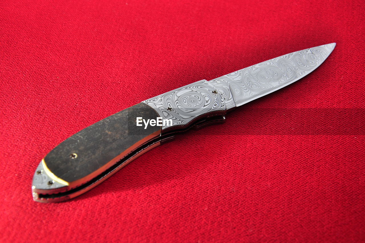 Close-up of penknife on red cloth