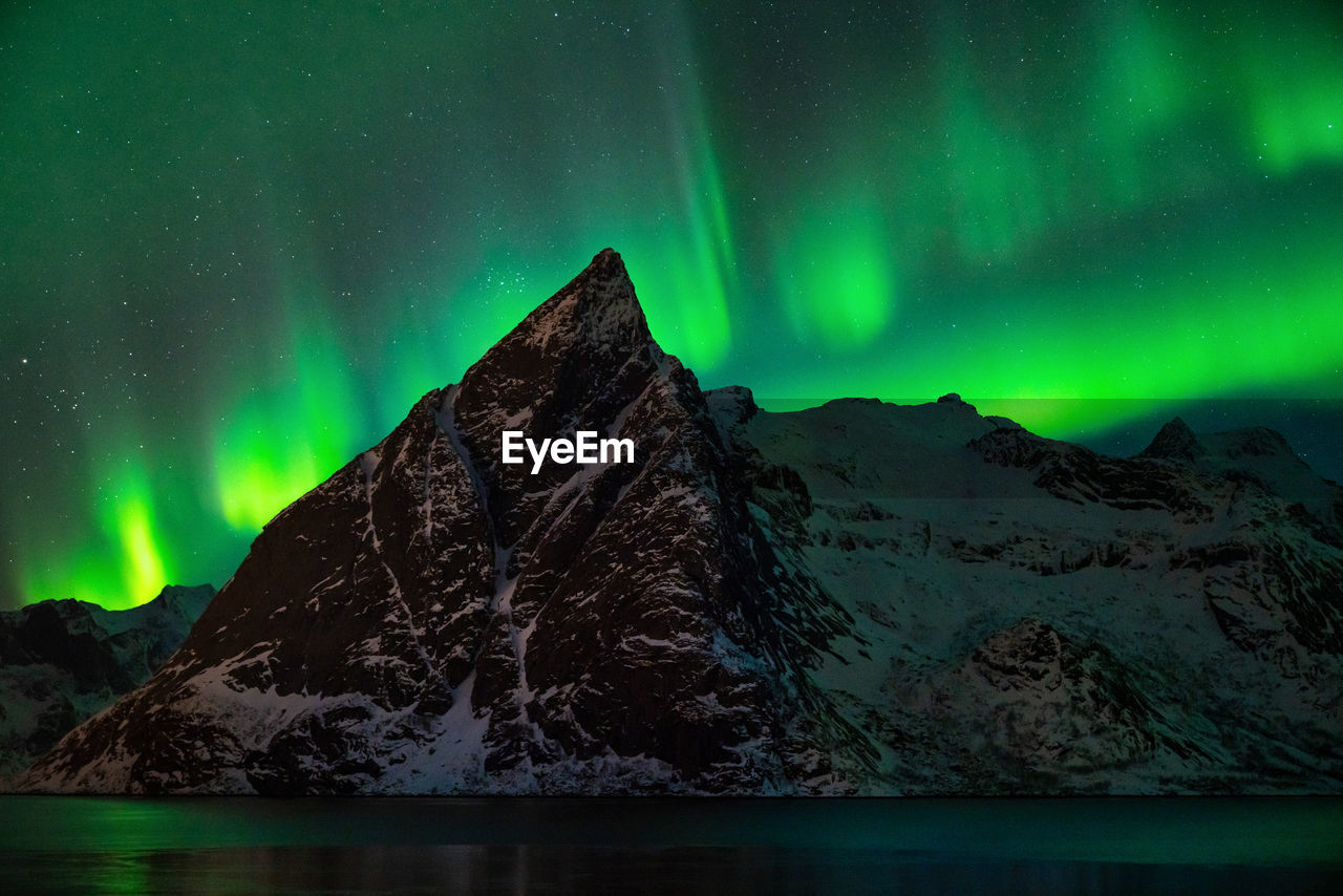 Scenic view of aurora borealis over snowcapped mountains at night