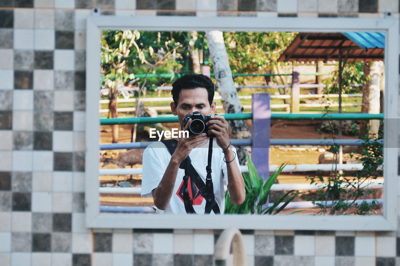 Reflection of man photographing in mirror