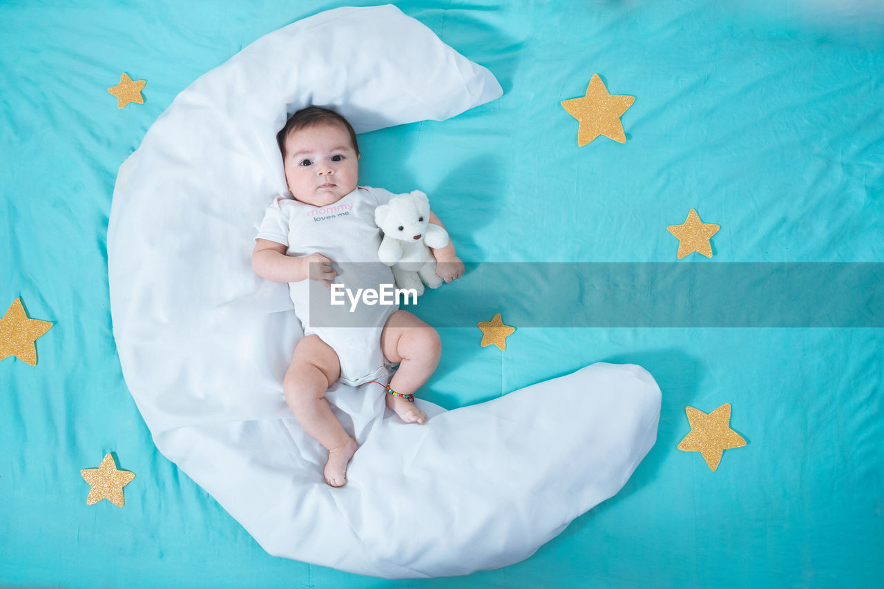 Beautiful latin baby girl, two months old, lying on a white sheet in the shape of a moon