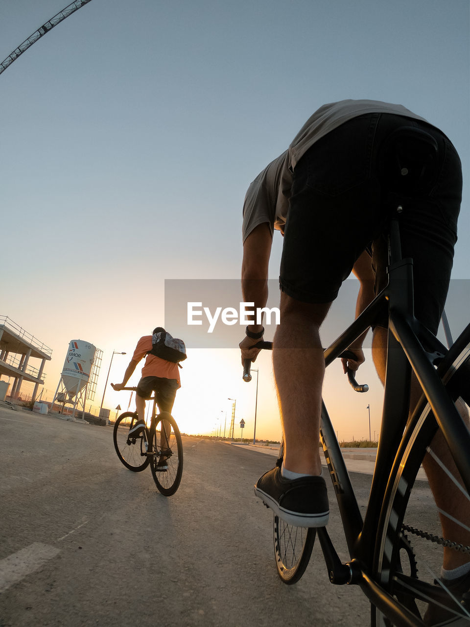 MAN RIDING BICYCLES ON ROAD AGAINST SKY