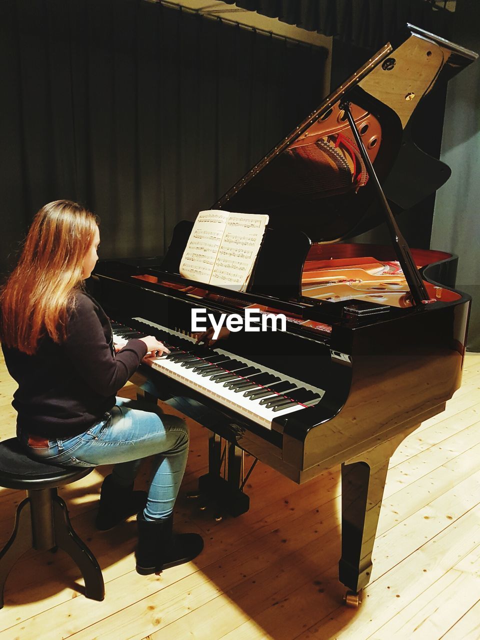 REAR VIEW OF WOMAN PLAYING PIANO