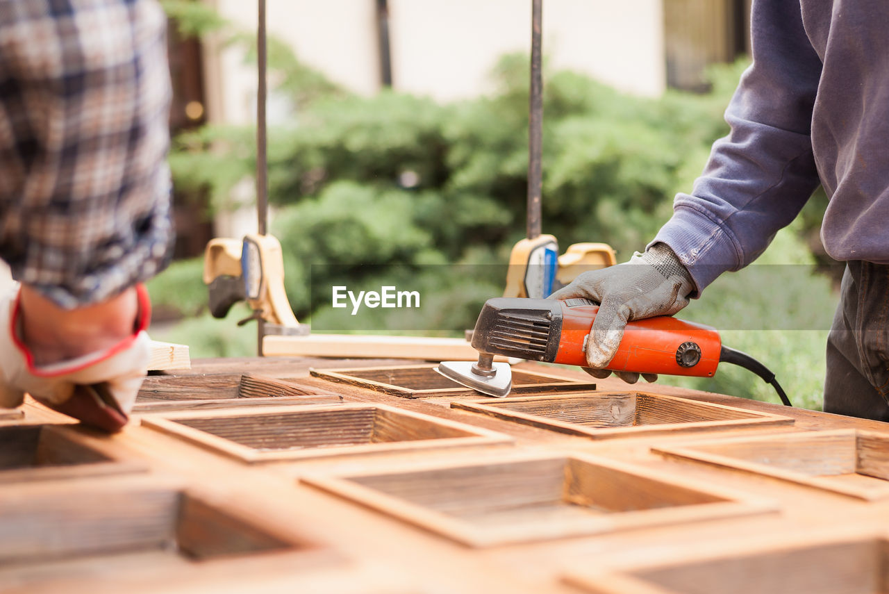 Midsection of men working on wood