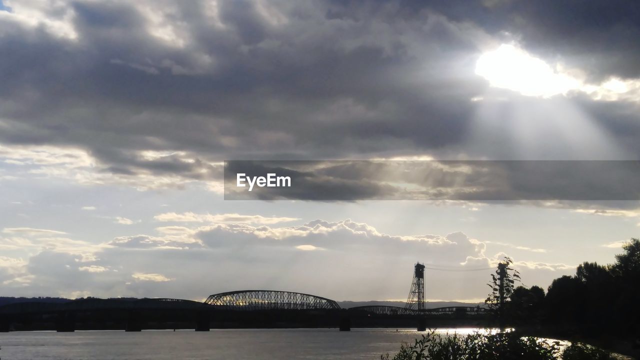 Low angle view of bridge over river against cloudy sky