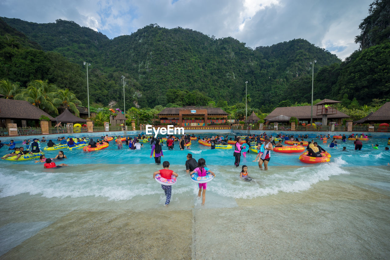 People in swimming pool against mountains