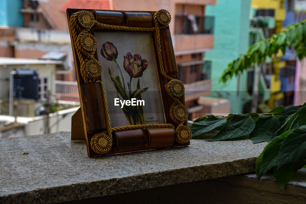 CLOSE-UP OF BUDDHA STATUE ON TABLE BY BUILDING