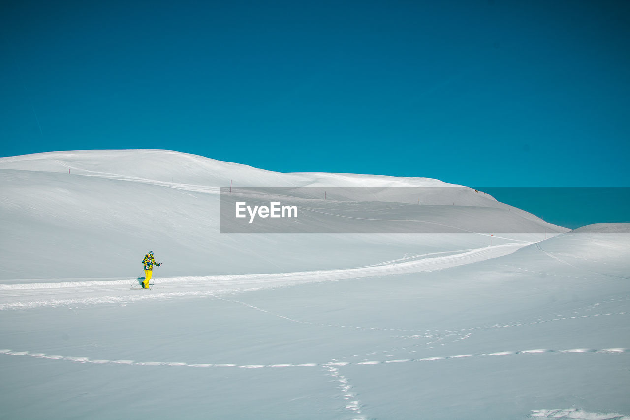 Person skiing on snowcapped mountain against blue sky