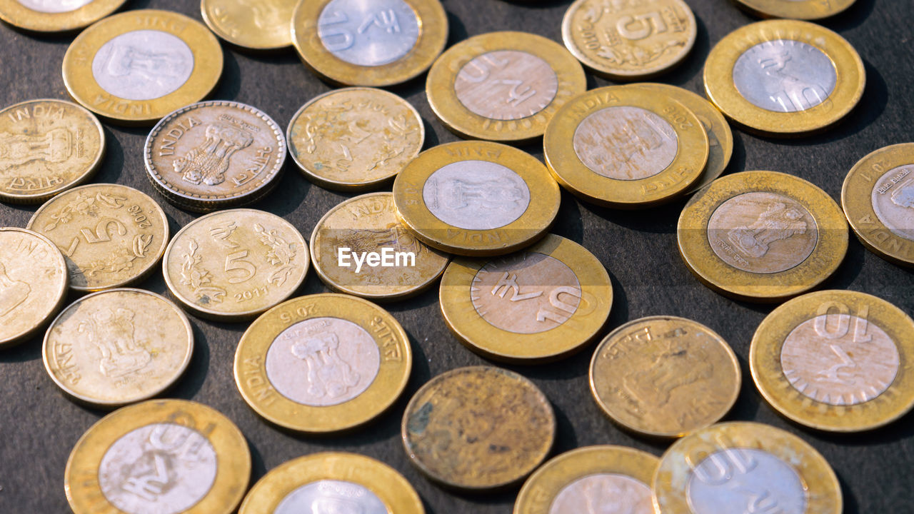 Heap of gold colored indian rupee coin currency on rustic floor. full frame. high angle view. 