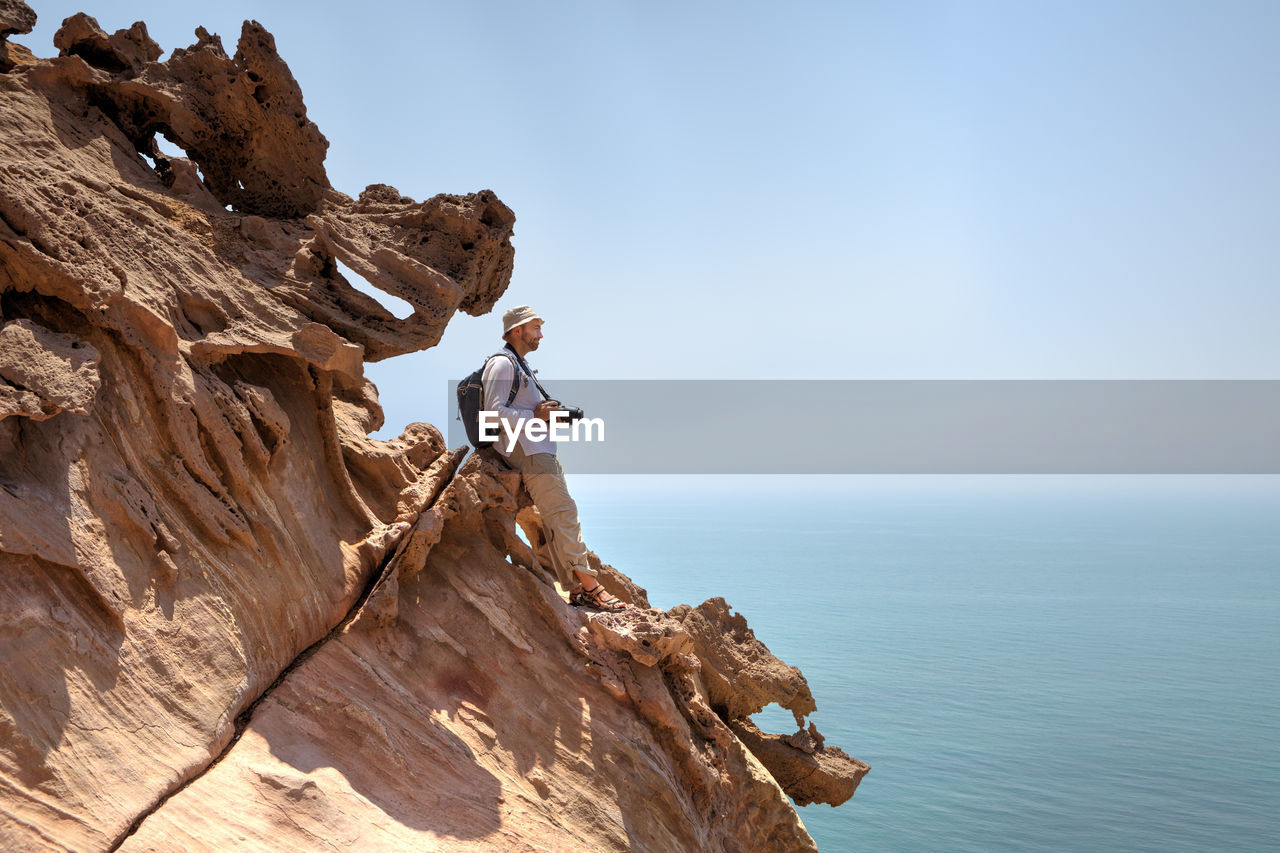 MAN ROCK ON SEA AGAINST SKY