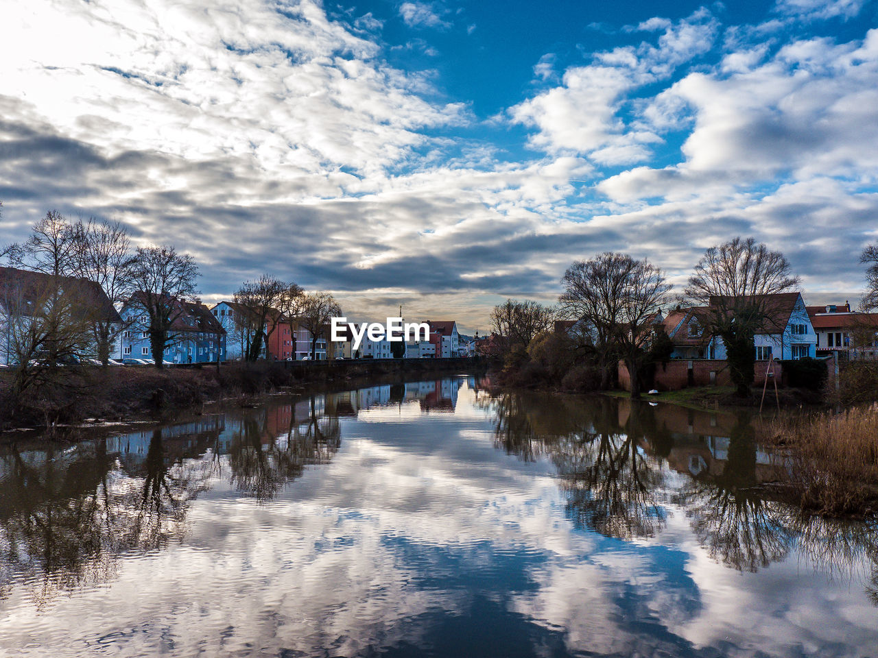 Reflection of trees in lake against sky in city