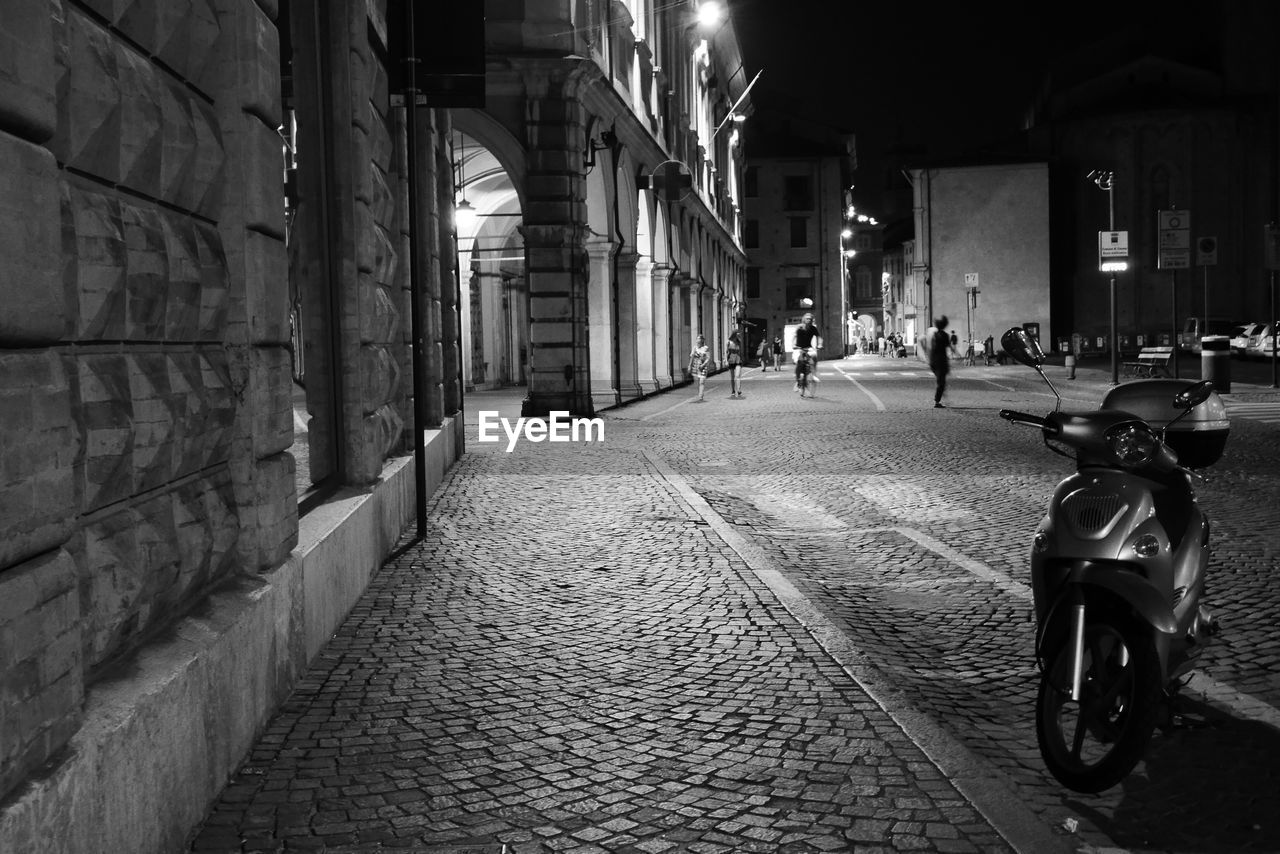 Man on walkway by street in city at night