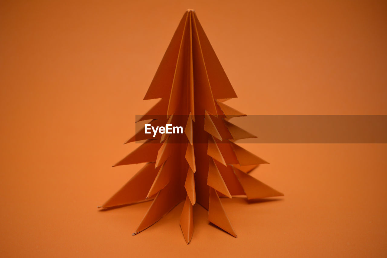 Orange origami christmas tree on a orange background.