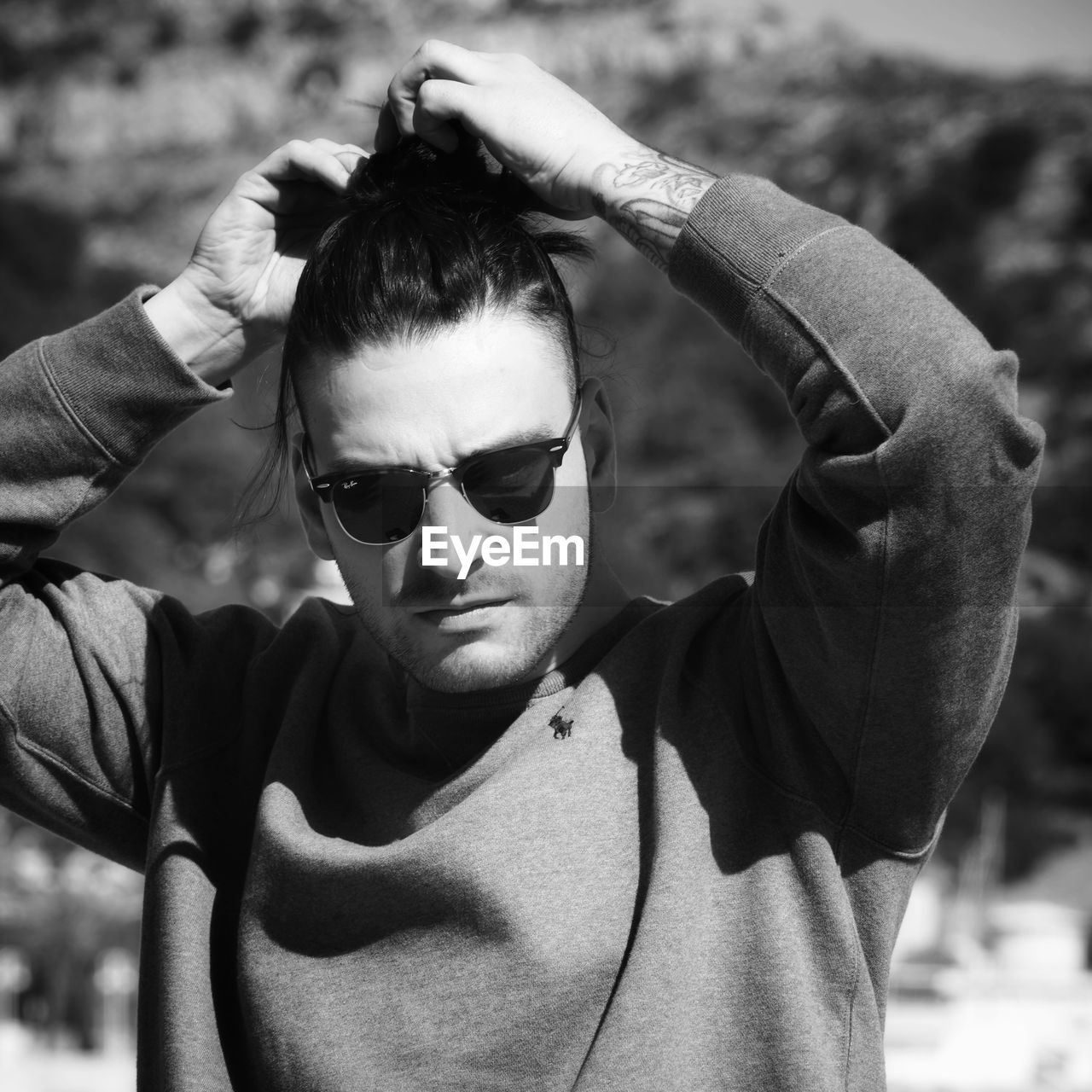 PORTRAIT OF YOUNG MAN WITH SUNGLASSES IN PARK