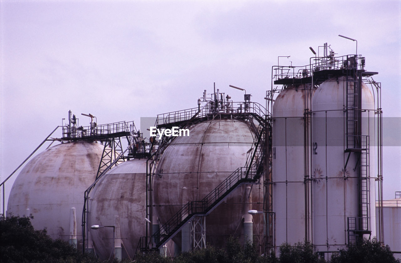 Low angle view of containers in factory against sky