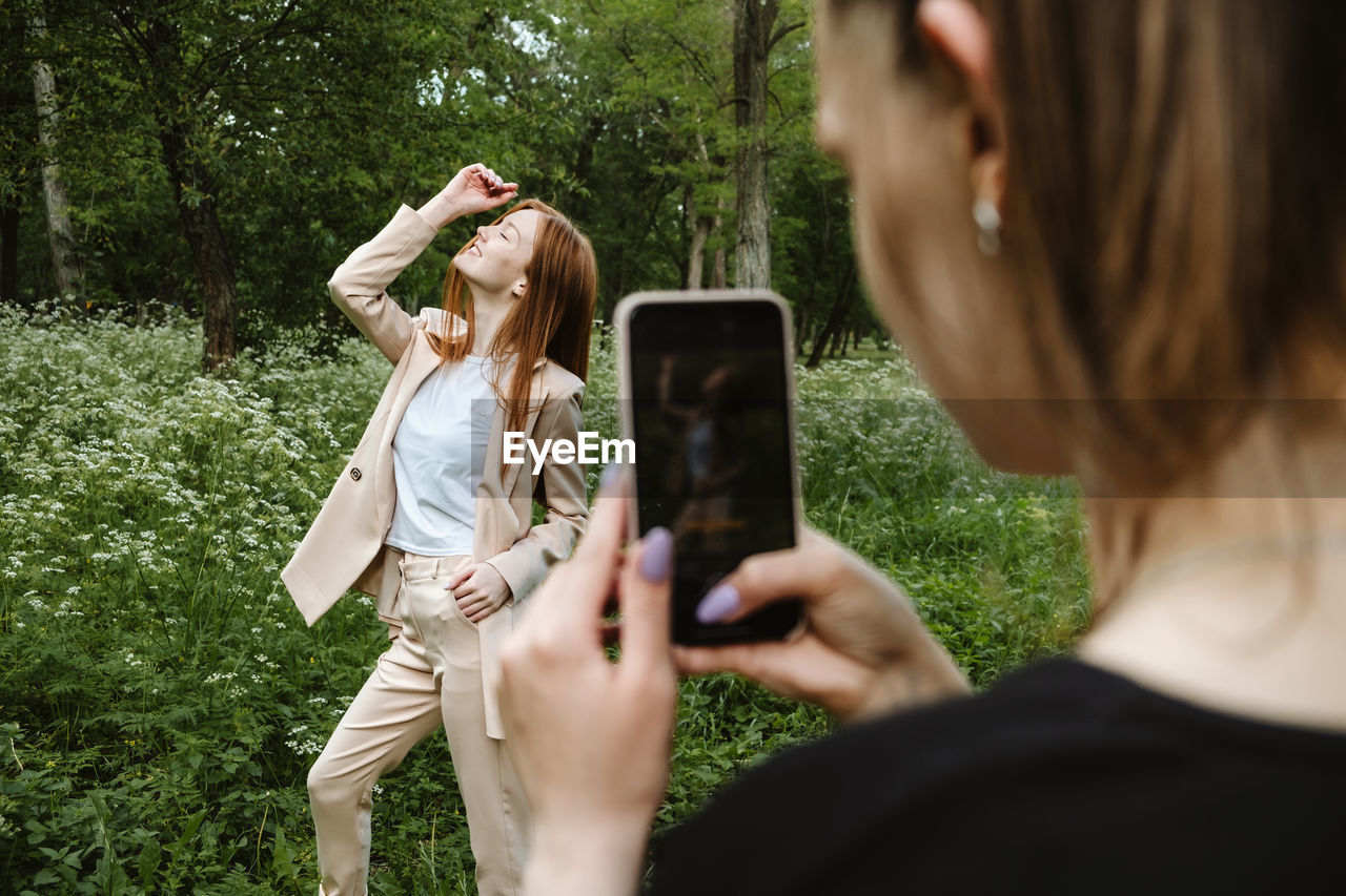 Rear view of woman photographing with mobile phone