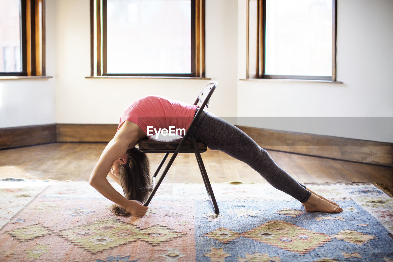 Woman stretching on chair at home