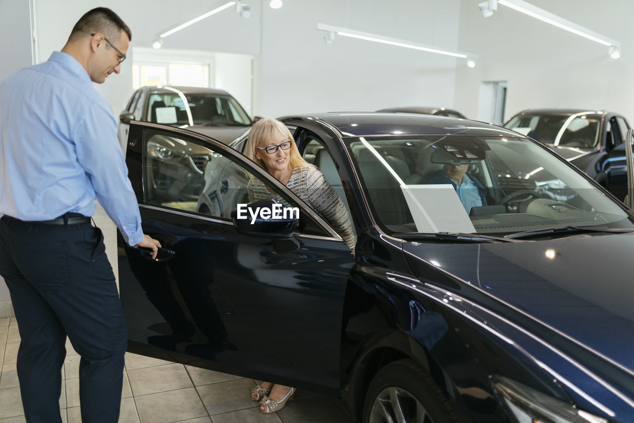 Salesman advising customers in car dealership