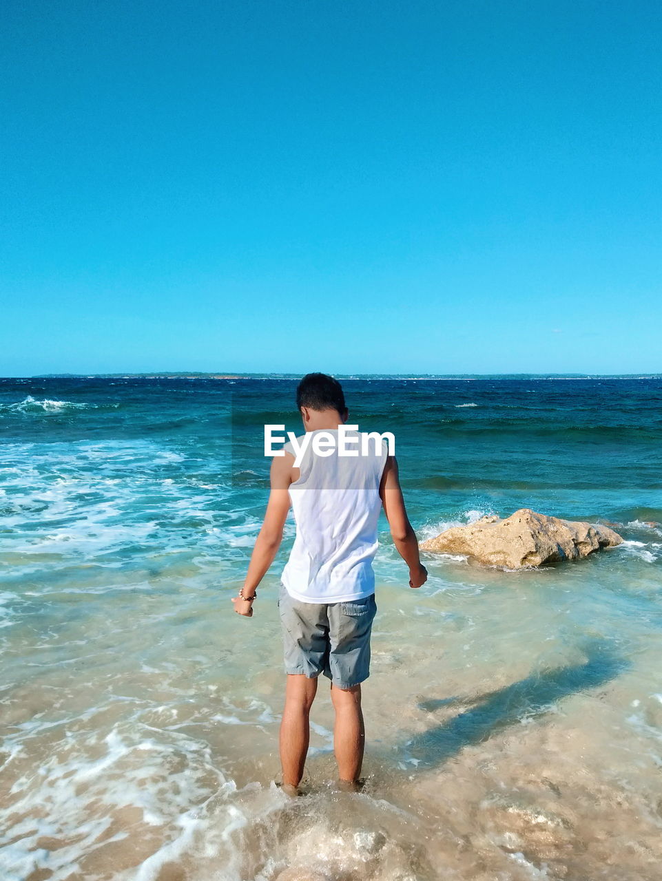 FULL LENGTH REAR VIEW OF MAN STANDING ON BEACH