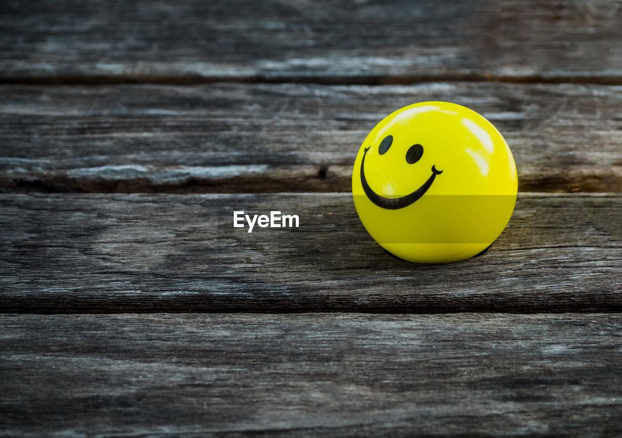 HIGH ANGLE VIEW OF YELLOW BALL ON WOODEN TABLE