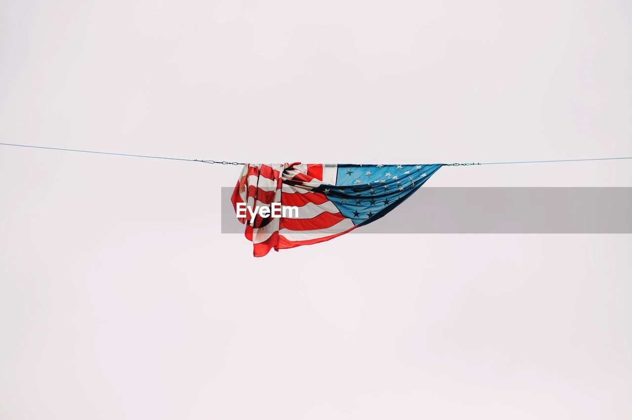 Low angle view of american flag hanging from rope against clear sky