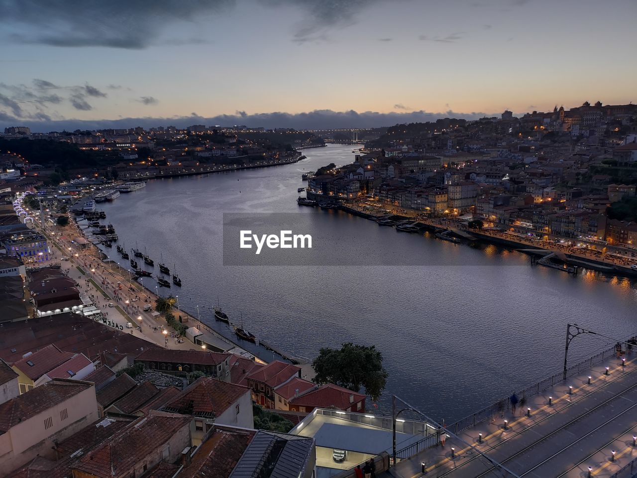 HIGH ANGLE VIEW OF RIVER BY ILLUMINATED BUILDINGS IN CITY