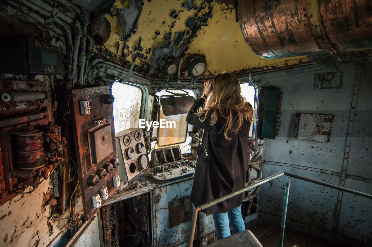 Rear view of woman standing in old abandoned train