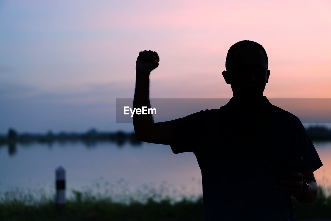 Rear view of silhouette man standing against sky during sunset