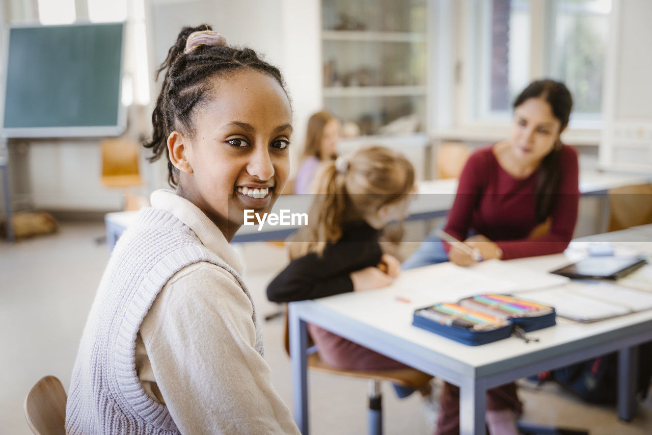 Side view portrait of smiling female student sitting in classroom