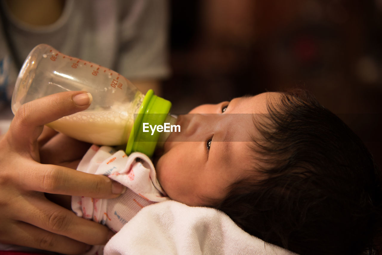 Cropped hand of person feeding baby