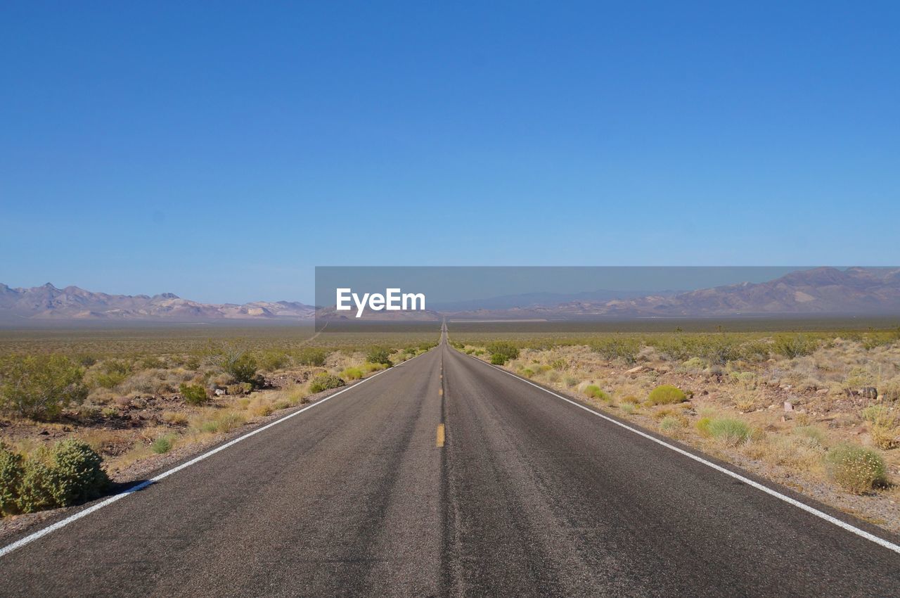 Road leading towards mountains against sky