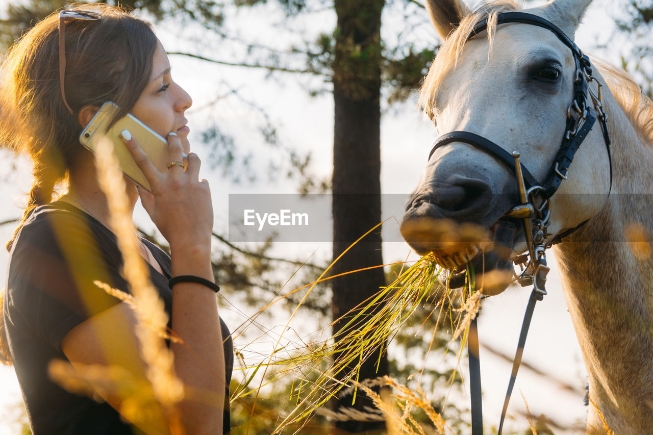 Woman talking on mobile phone by horse 