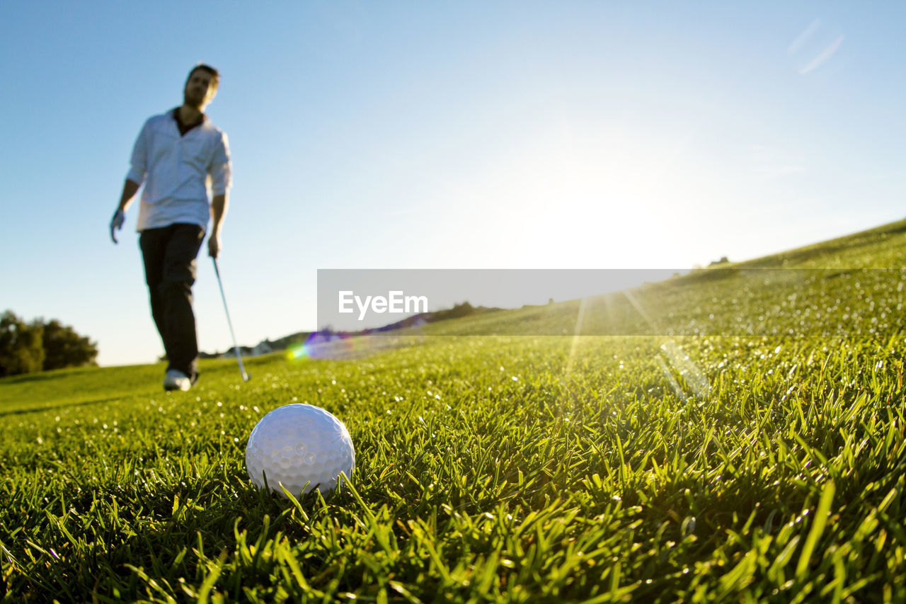 Man standing on golf field against clear sky