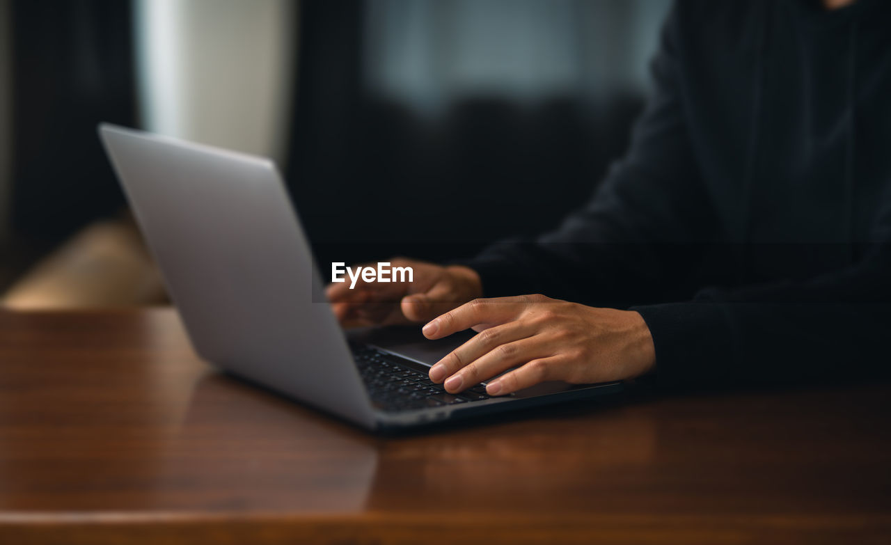 midsection of woman using laptop at table