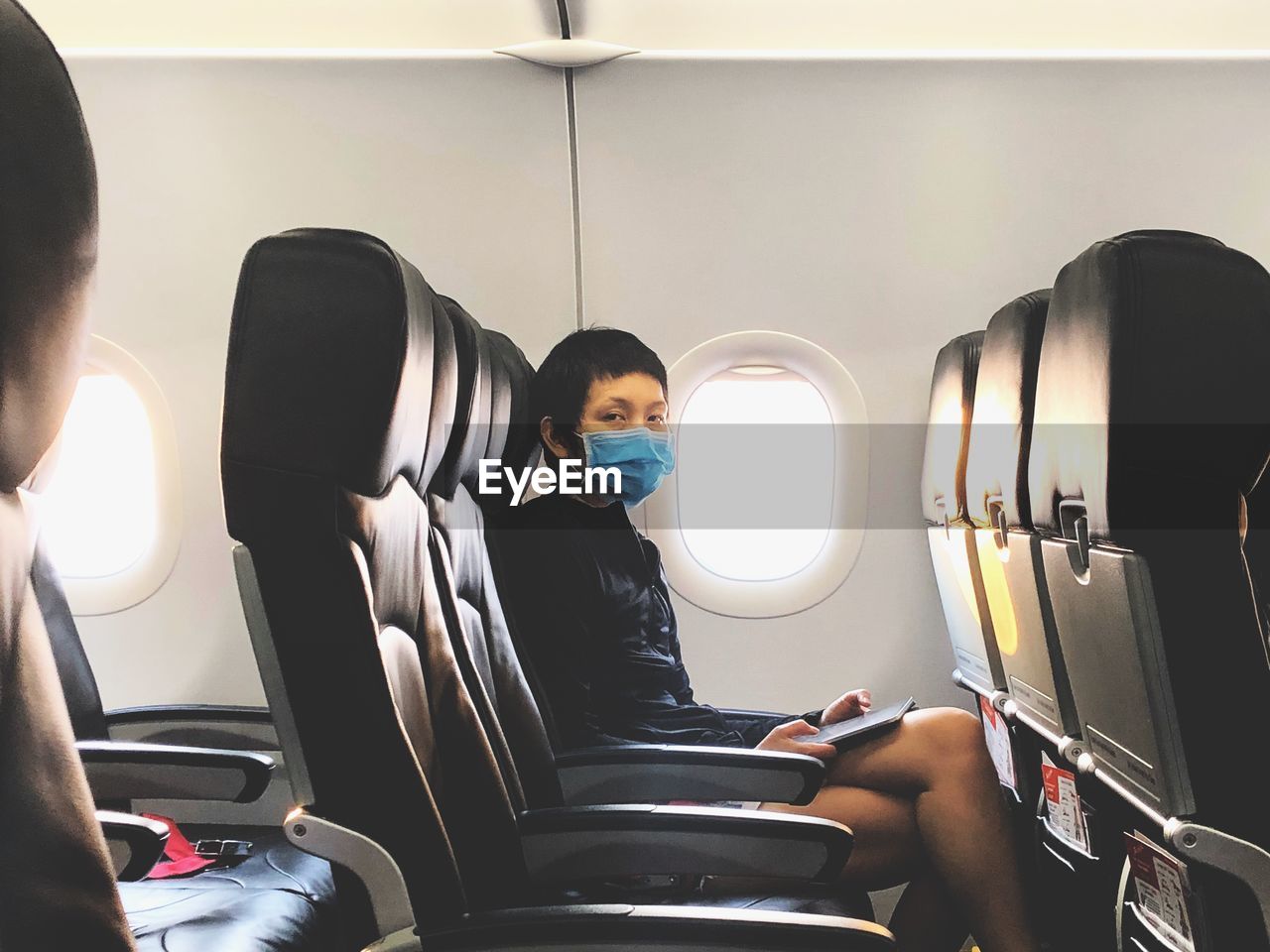 Portrait of man wearing mask sitting in airplane