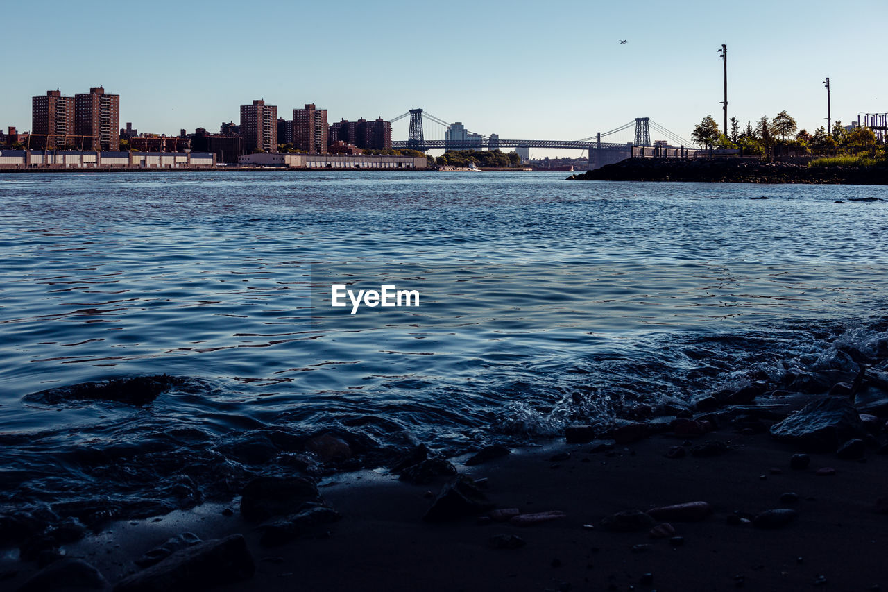 SEA BY BUILDINGS IN CITY AGAINST SKY