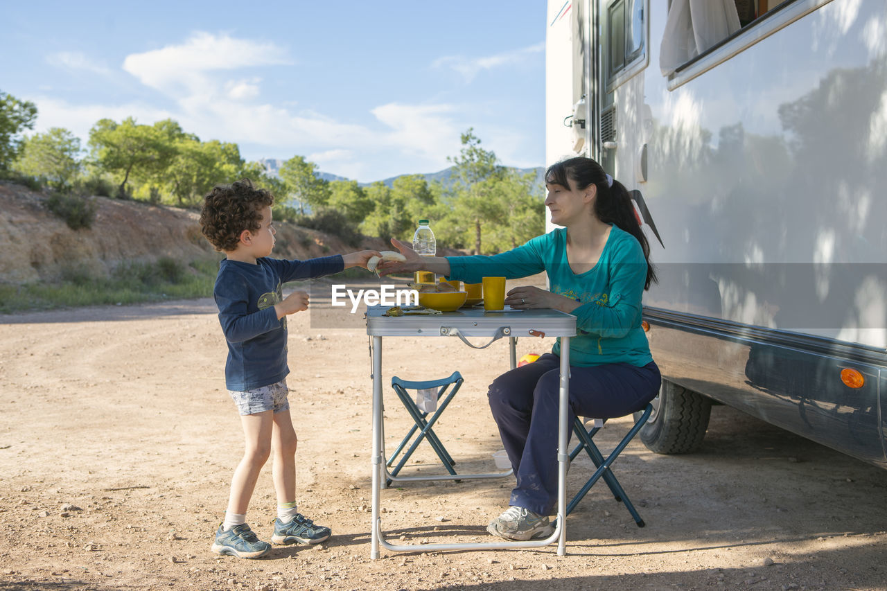 Mother and son at camping table next to motorhome