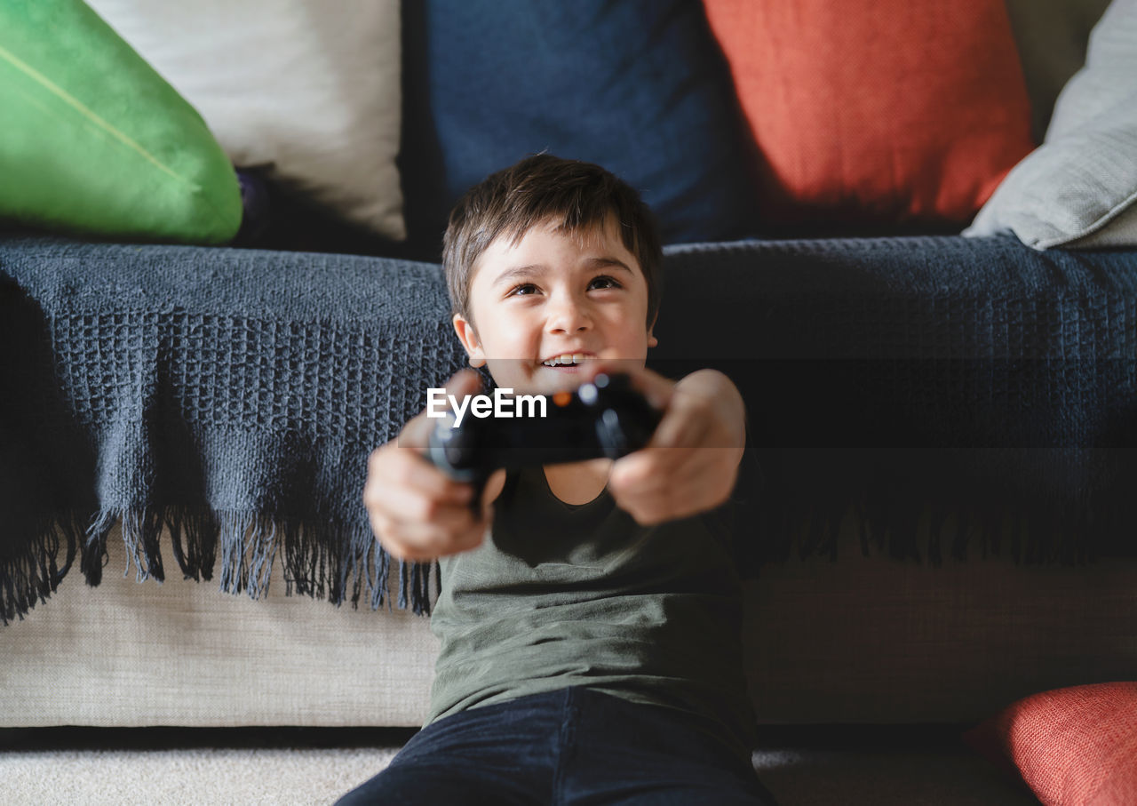 Full length of boy relaxing on sofa at home